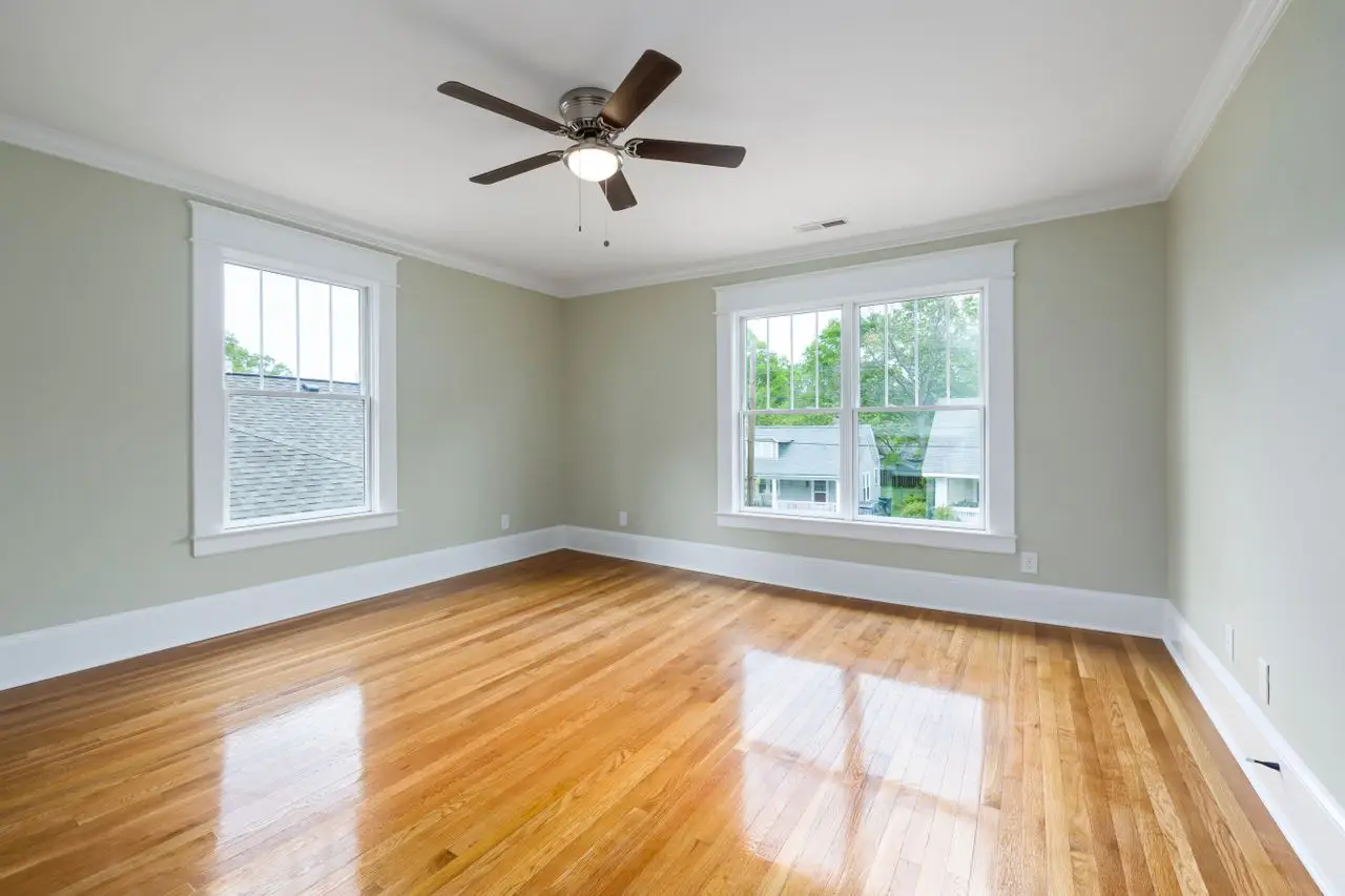 Bright empty room with wooden floors, large windows, and a ceiling fan. West bench- Boise, ID