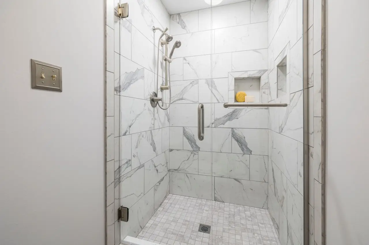 Elegant bathroom with white marble tiles and glass door, showcasing interior design. installed in Eagle ID