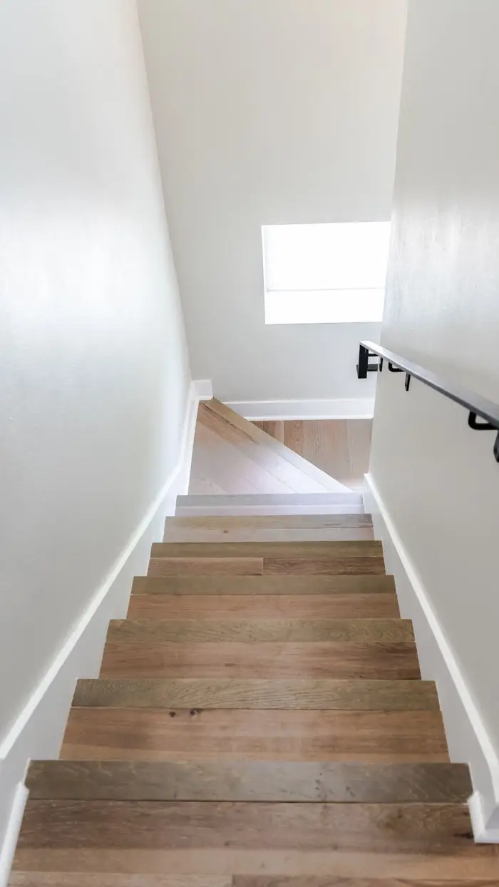 Bright minimalist staircase with wooden steps and metal handrail in a modern home interior. LVP-Stairs- SW Boise